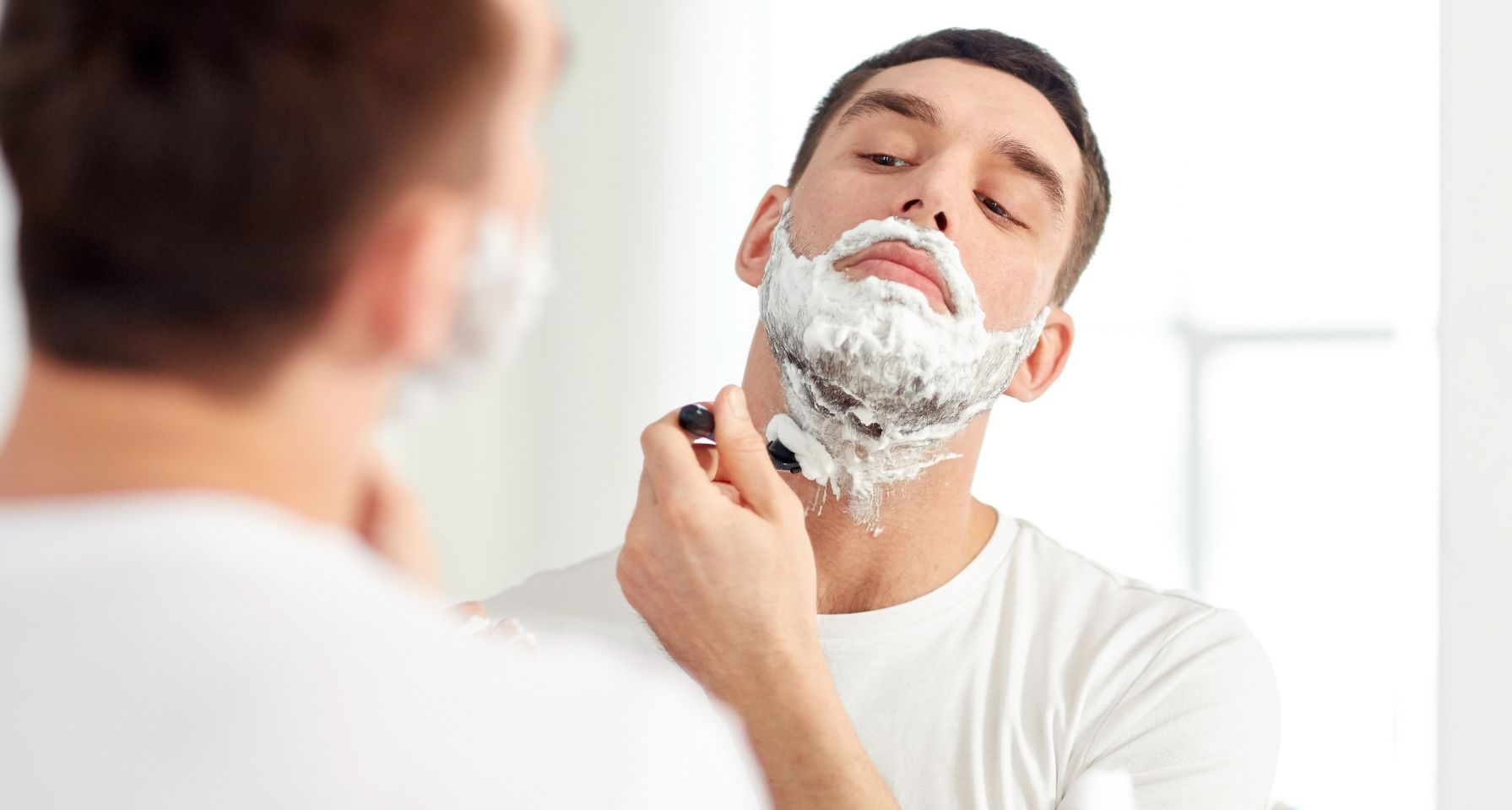 hombre afeitándose la barba frente al espejo